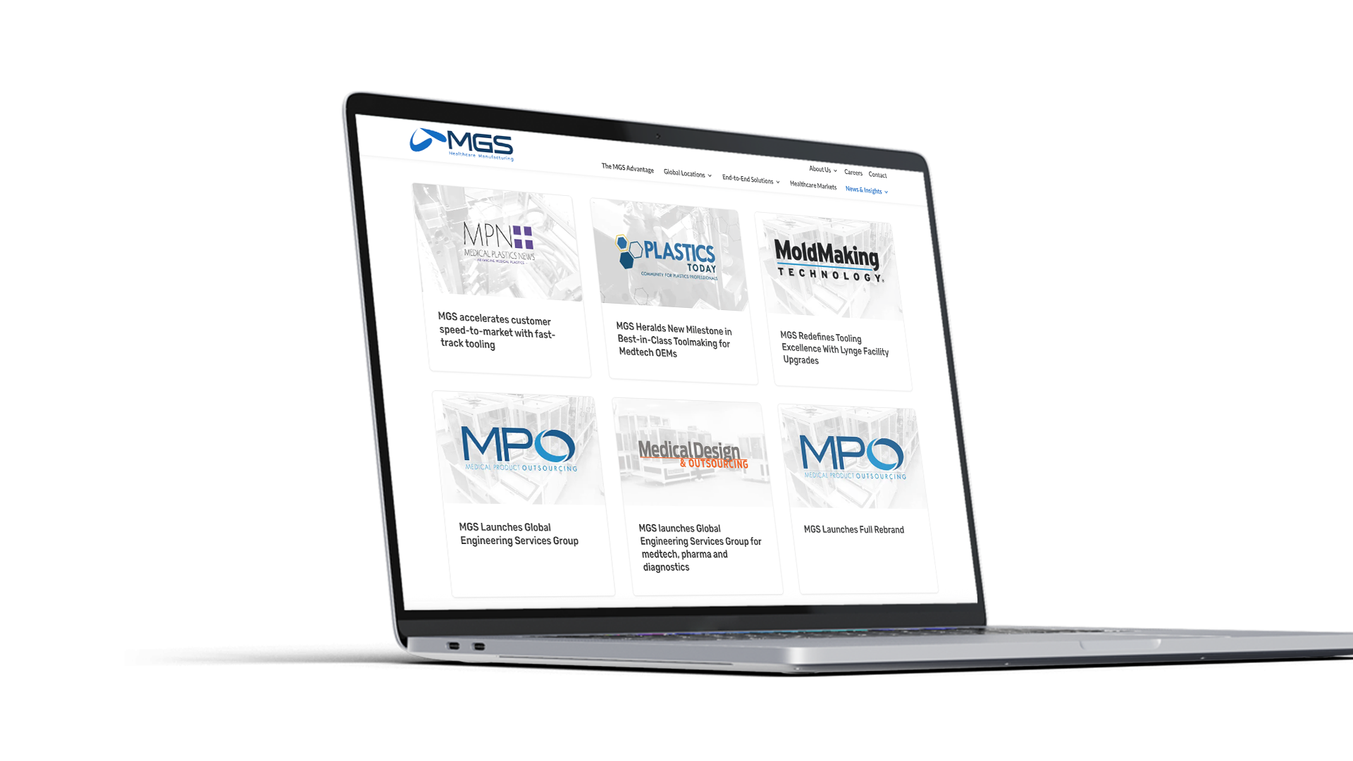 A laptop displaying a website with the MGS logo, featuring various news articles and logos related to plastics, moldmaking, and medical design industries. The screen shows six article previews in a grid layout.
